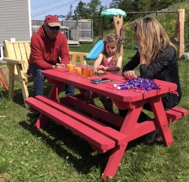 Kids picnic table painted red and showing a child and adult sitting at the table